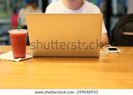 Man working on laptop with juice drink in cafe shop