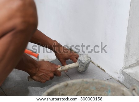 Man laying floor tile with rubber hammer tile with rubber hammer