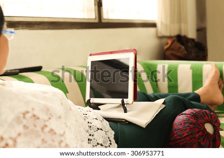 Elderly woman working with laptop on the couch