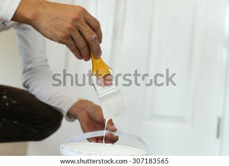 Painter hand holding yellow paint brush for decorating