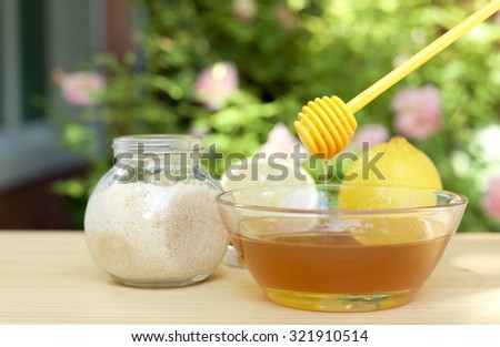 Bowl of honey and sugar and lemons on wooden table