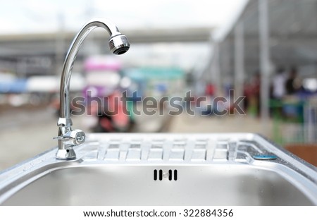 Water tap on stainless steel kitchen sink on worktop
