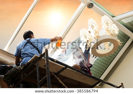 unidentified  people wrappers tinting a glass house window with tinted foil or film using foggy spray