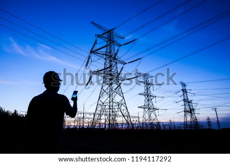 Power workers at work, silhouettes of power towers