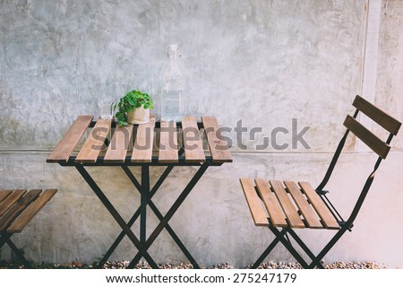 Outdoor table and chair on concrete background at coffee shop vintage color
