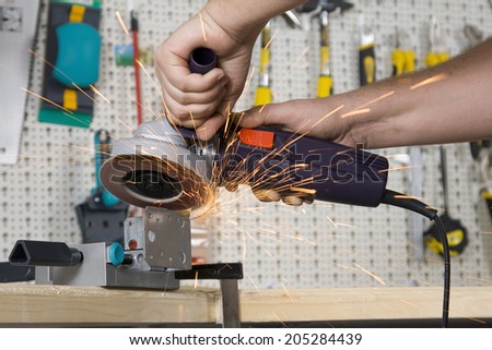 Worker with angle grinder, close up picture on tool, hands and sparks