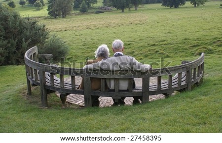 Elderly couple sitting together relaxing on a semi circular wooden bench