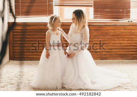 Mother and daughter like brides in white dress.