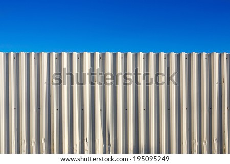 Corrugated white metal fence and blue sky