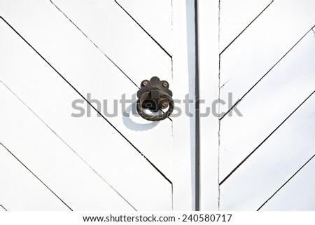 Black metal door knob (handle) on the white wooden door with grunge texture. Mediterranean Europe style.