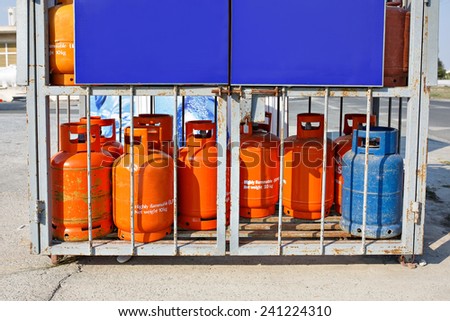 Old used gas bottles cylinders storage. Propane, butane. Bright orange and blue colors. Empty space for your text.