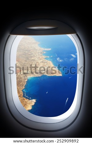 Approaching island holiday destination, jet plane window sea land view. Travel resort concept.