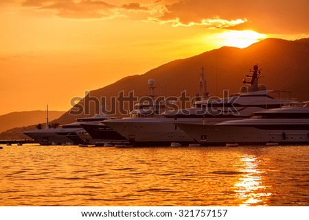 Yachts parking in marina. Mooring yachts and boats. Mountains and sunset background.