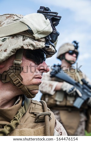 US marine half-turned to the camera. His brother-soldier looking in the same direction