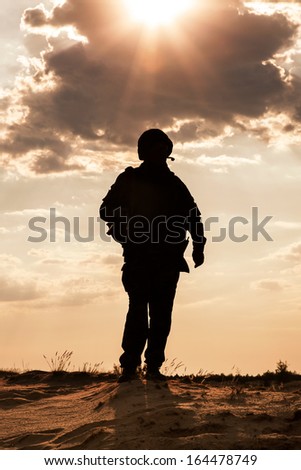 Silhouette Of Young Soldier In Military Helmet Against The Sun