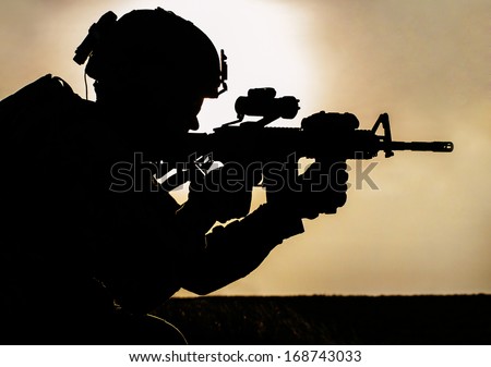 Silhouette of young soldier in military helmet against the sun Silhouette of young soldier in military helmet against the sun