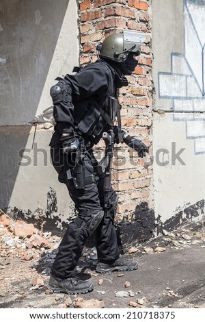 Spec ops soldier in black uniform and face mask aiming his pistol
