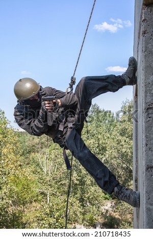 Spec ops soldier in face mask during rope exercises with weapons