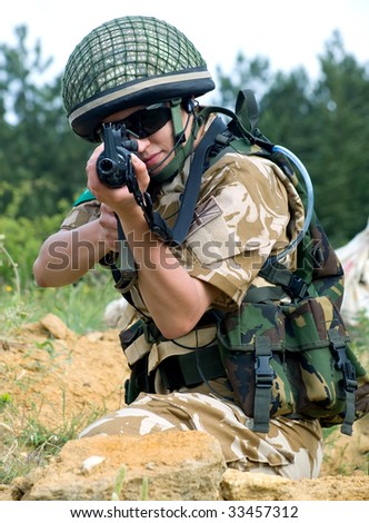 stock photo : British girl soldier in desert uniform aiming her rifle