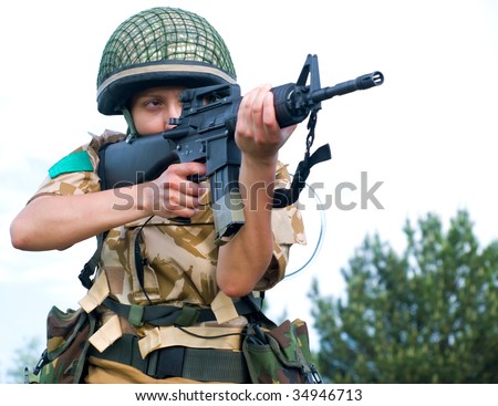 British girl soldier in desert uniform aiming her rifle