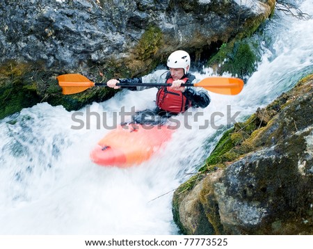 An active kayaker, shooting a raging waterfall among the rocks