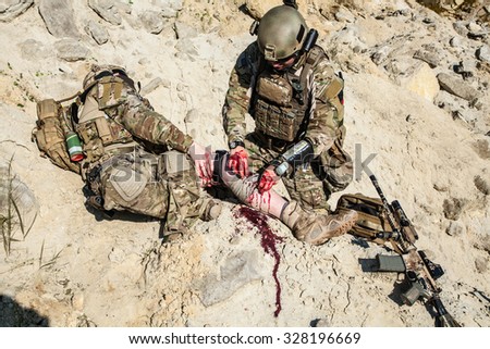United States Army ranger medic treating the wounds of his injured fellow in arms in the mountains