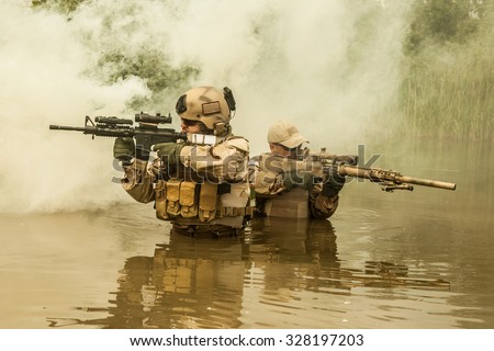Navy SEALs crossing the river with weapons