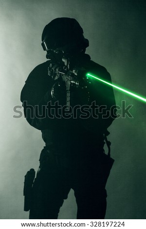 Police officer SWAT in black uniform in the smoke with laser sights