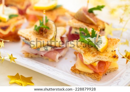 Star shaped toasts with smoked salmon, meat  and cheese.