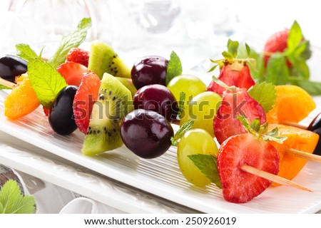 Fresh summer fruits on sticks. With mint leaves. Tilt-Shift. Focus is on first stick of fruits.