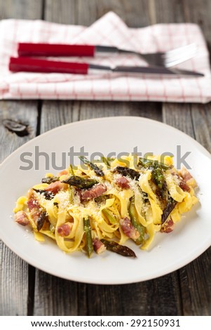 Italian pasta carbonara with asparagus. On wooden rustic table.