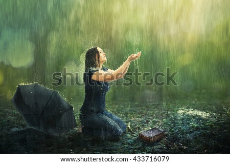 A woman enjoys a rain shower in the forest.