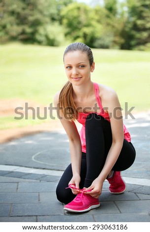Female sport fitness runner getting ready for jogging outdoors on forest path in spring or summer.