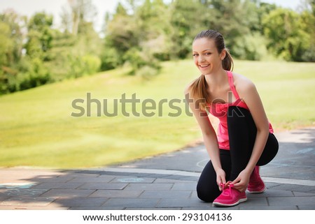 Female sport fitness runner getting ready for jogging outdoors on forest path in spring or summer.