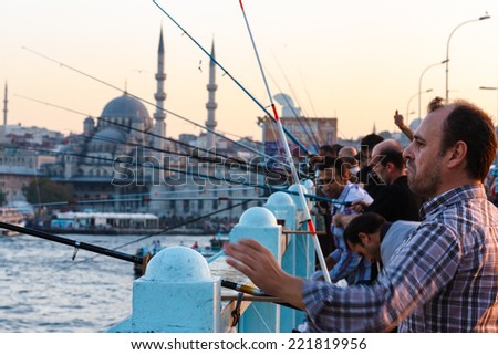 ISTANBUL, TURKEY - September 27, 2012: A group of men fish on the Galata Bridge during the sunset.