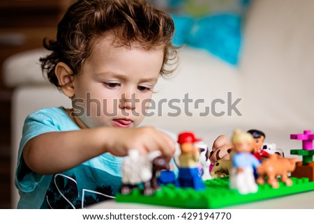 A baby boy playing with lego/ construction toy blocks at home. Kids playing. Children at day care. Child and toys.