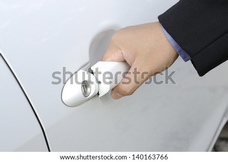 Chauffeur or driver hand opening white car door