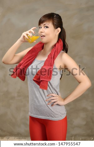 Woman drink orange juice after exercise in the gym