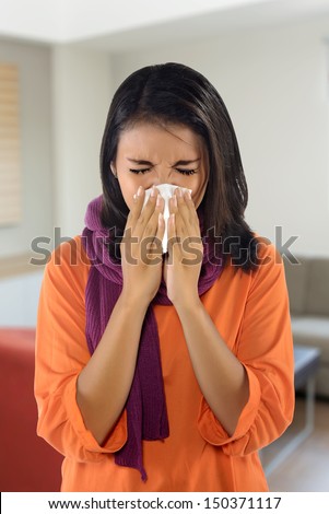 Young woman with handkerchief having cold. With living room background