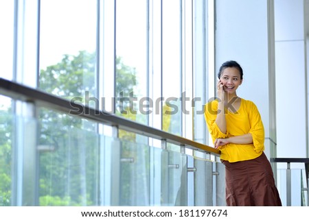 Business woman in yellow shirt using cellphone in the office