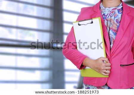 Woman in pink suit, writing something on paper. You can put your design on the paper