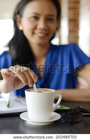 Young Female stir cup of coffee in the morning at Cafe