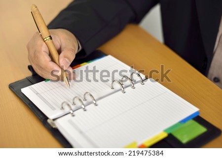 Business man writing on agenda over office desk