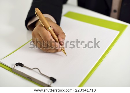 Business man writing on clipboard on the desk