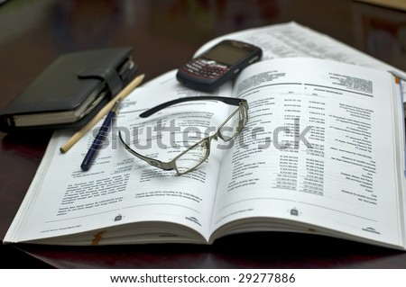 Accounting book, pen, organizer, glasses, PDA and blackberry in the office