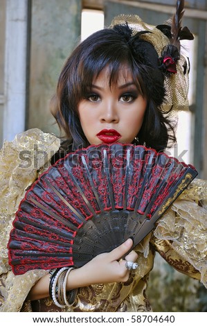 Chinese woman wearing victorian costume holding a fan, shoot at grunge building