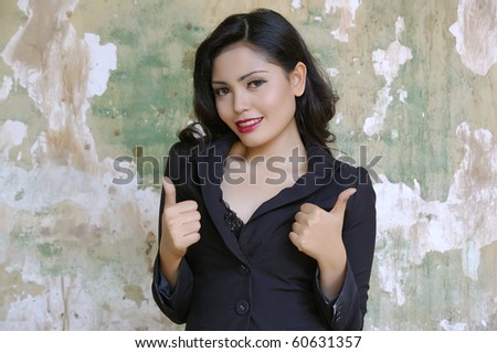 Pretty business woman wearing black suit, posing at outdoor, give thumbs up