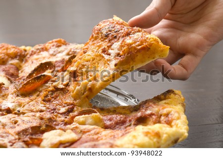 A Hand take a slice of pizza from the pan