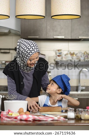 Moslem woman wearing hijab, teaching her daughter make halal food