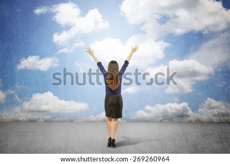 Back view of business woman looking at grunge blue sky. Conceptual Image